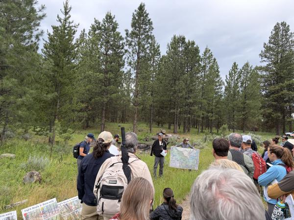 field tour group gathers in a meadow to listen to a presenter
